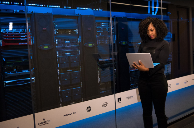 Developer standing near servers with a laptop in hand